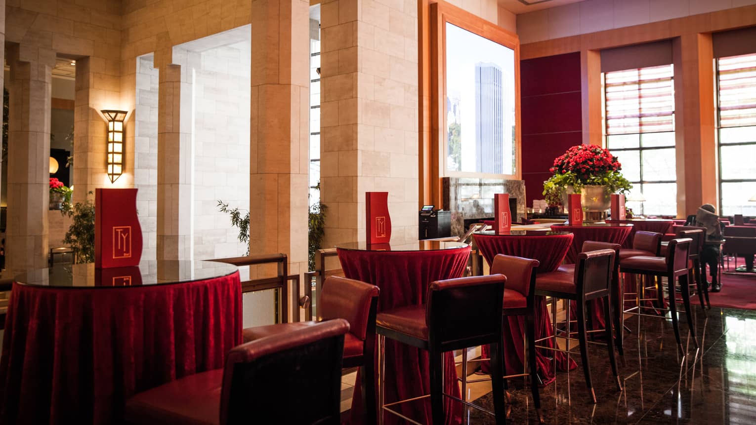 Tall red stools around round cocktail lounge tables with red Ty Bar menus