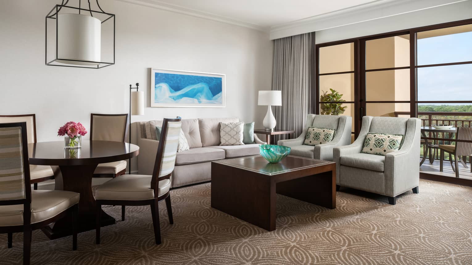 Living room with beige sofa, two arm chairs, wooden coffee table, round dining table and four chairs
