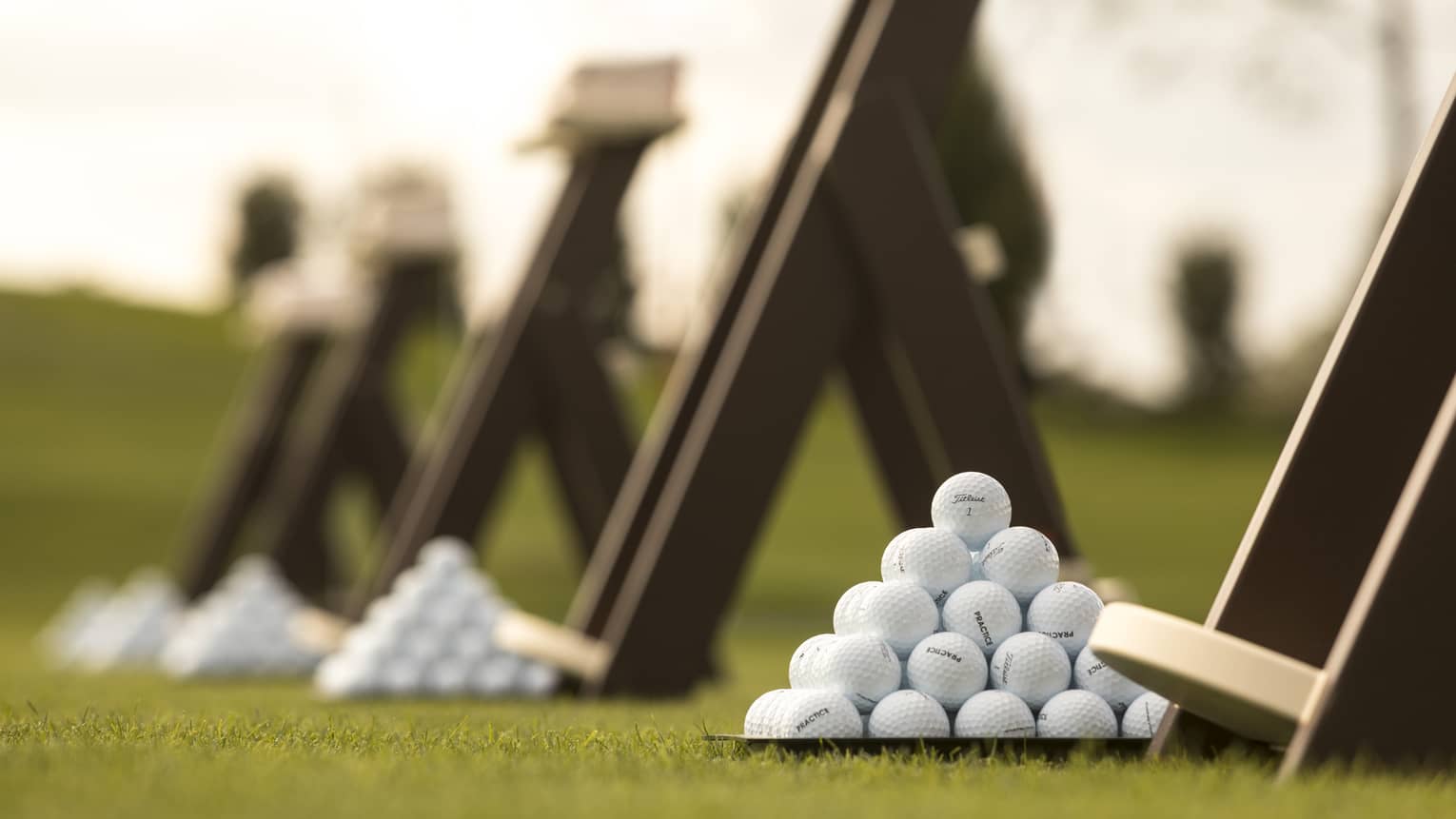 Stacks of white golf balls on lawn in front of wood panels