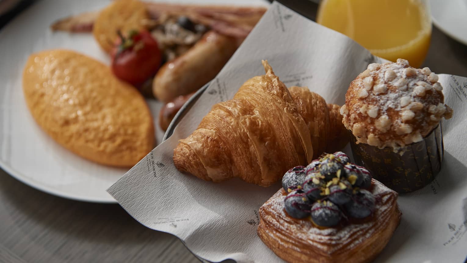 In-room dining breakfast spread with bakery items and orange juice