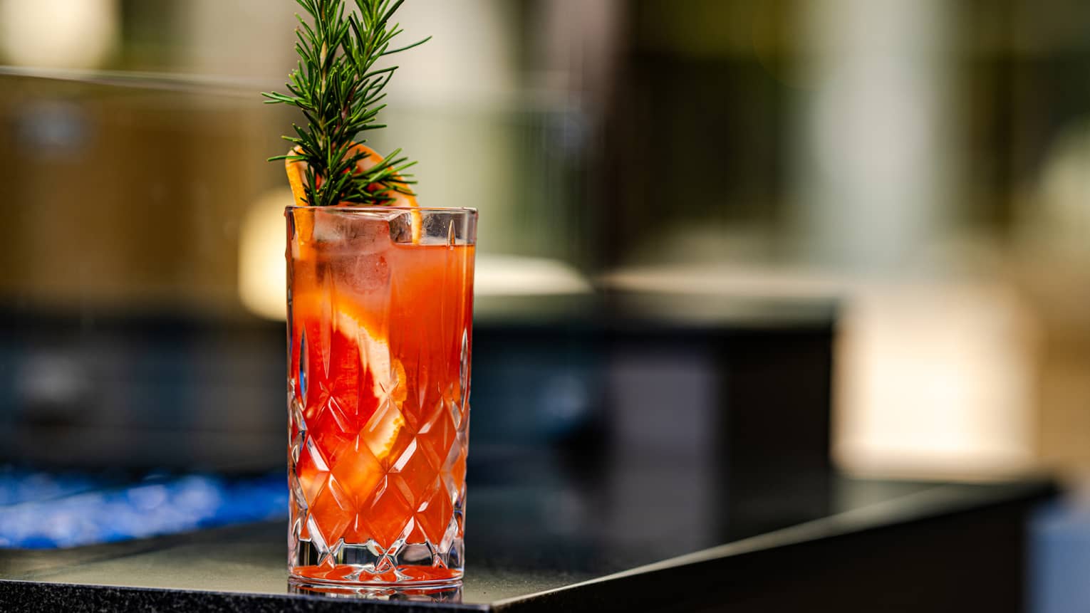 A glass with a red beverage and a fruit slice in it