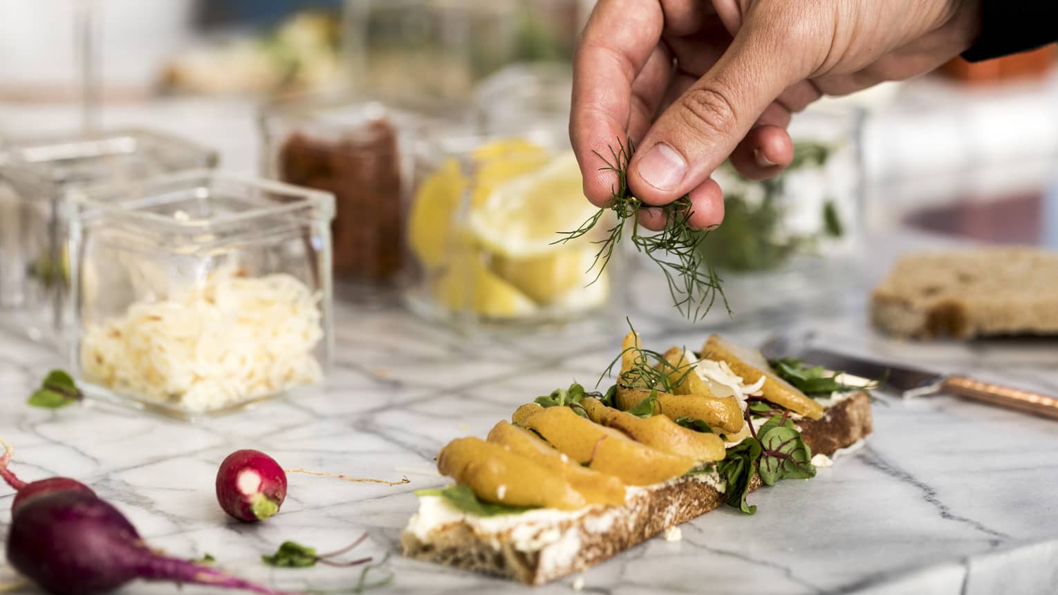 Culinary class, close-up of hand garnishing herbs on gourmet flatbread near ingredients