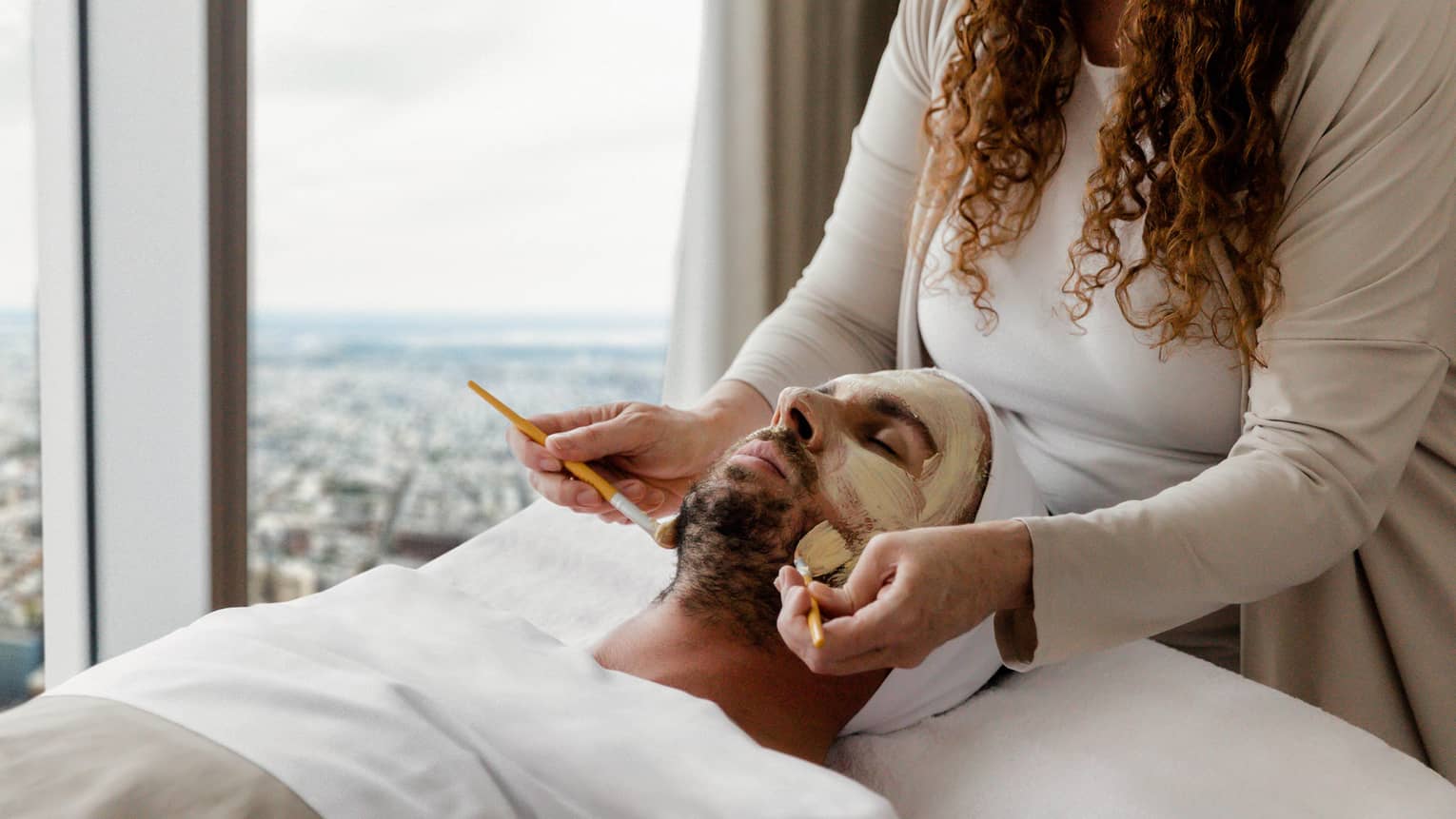 Green face masque being put on man.