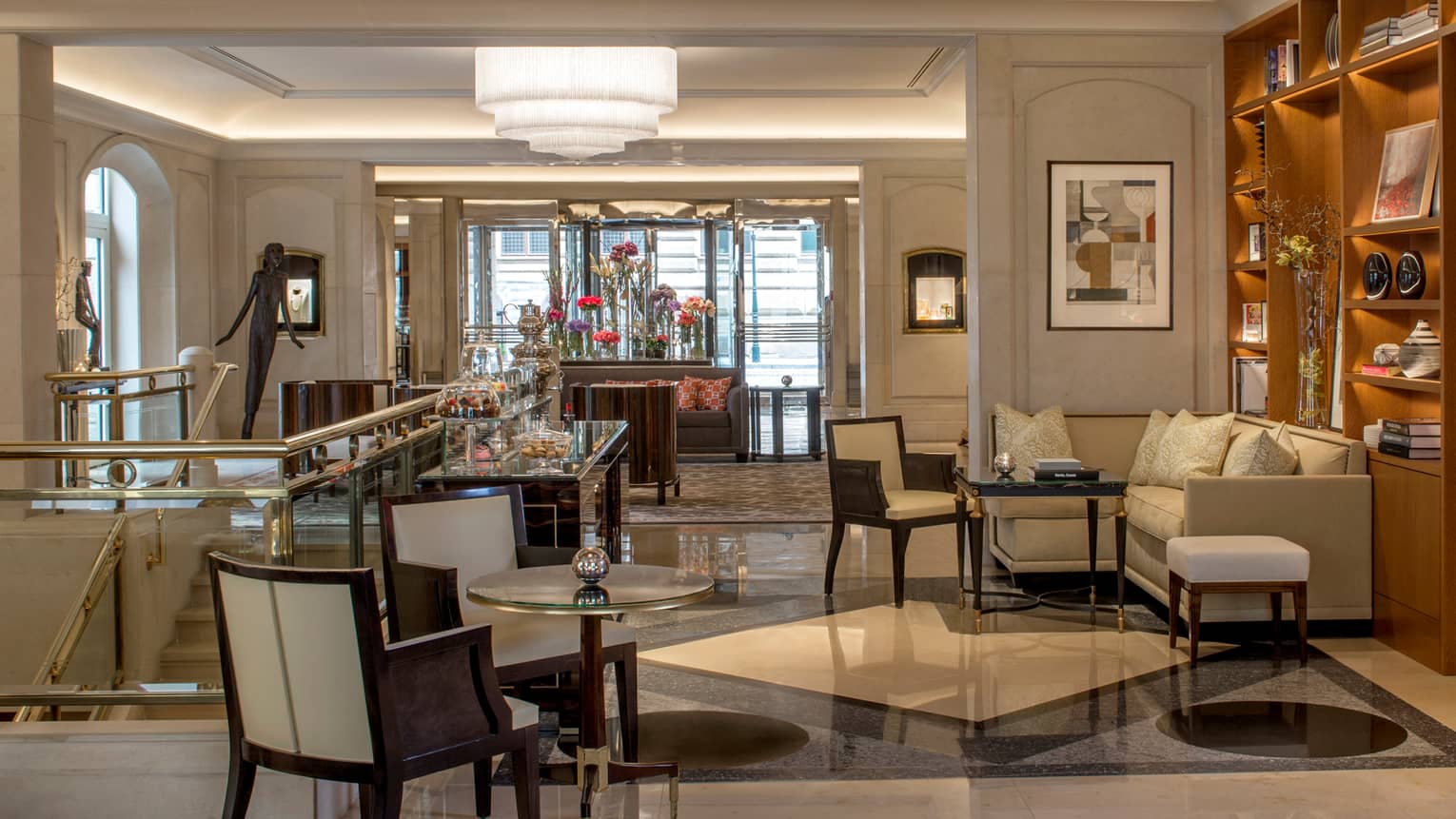 Lounge hallway beside staircase, cafe table and chairs, small L-shaped sofa, dessert cart