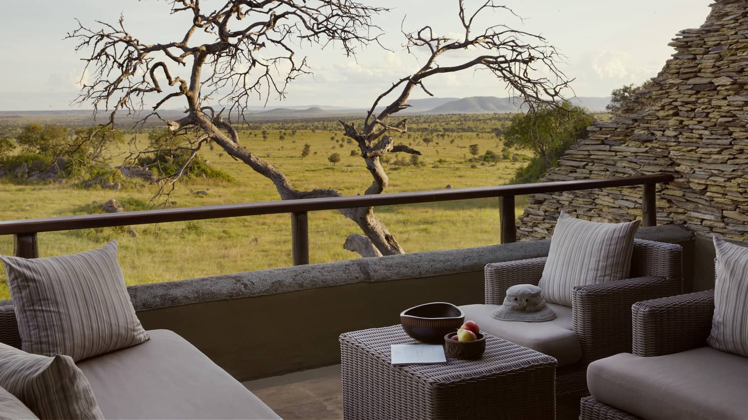 Villa terrace with beige seating with leafless tree near railing and expansive plains-to-mountains view