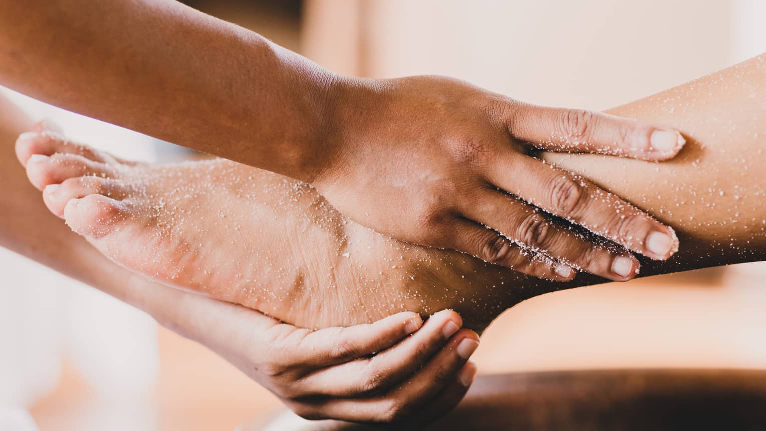 Hands hold a person's foot and ankle in a spa