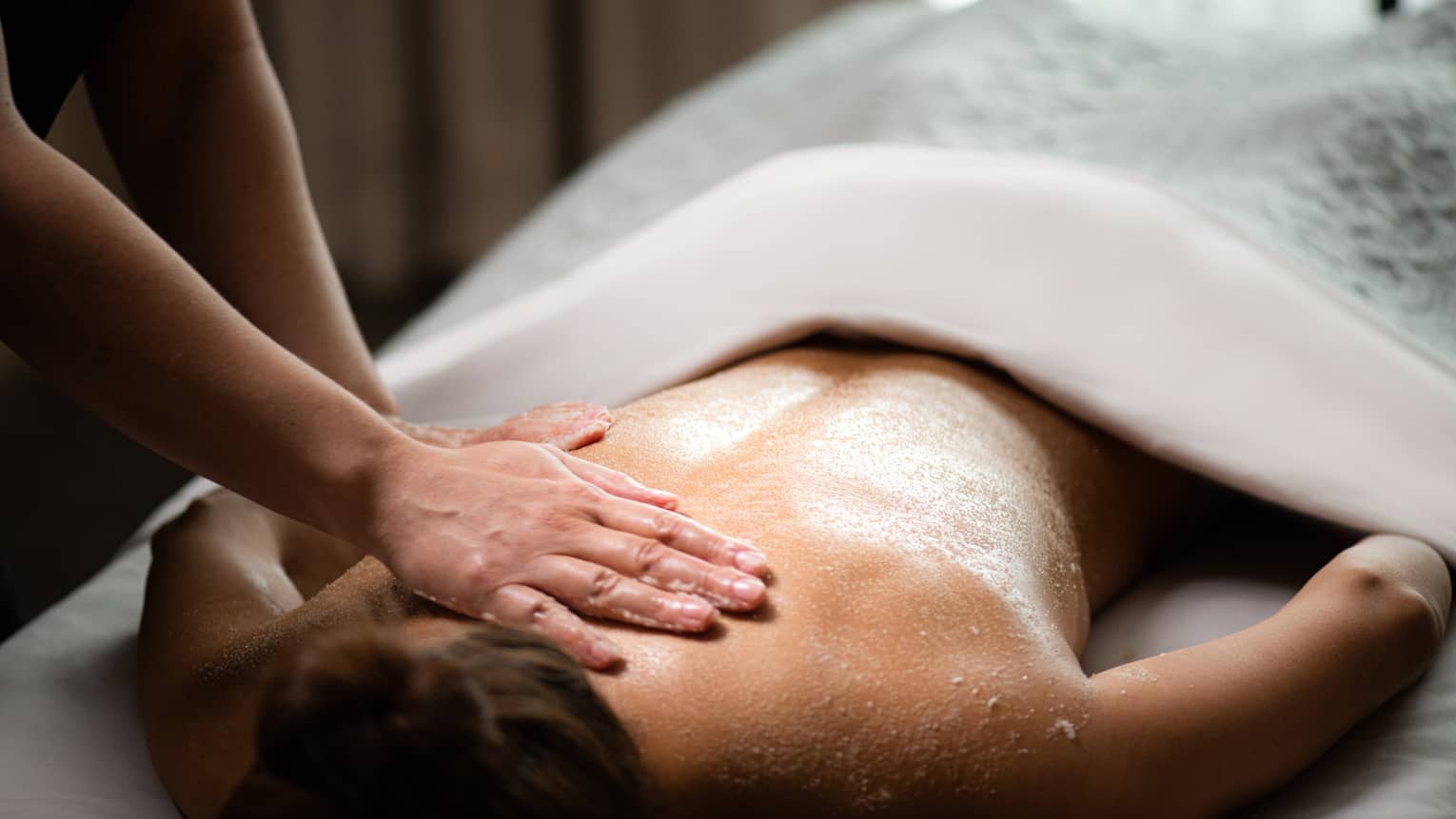A woman being massaged by a spa staff member while lying down.