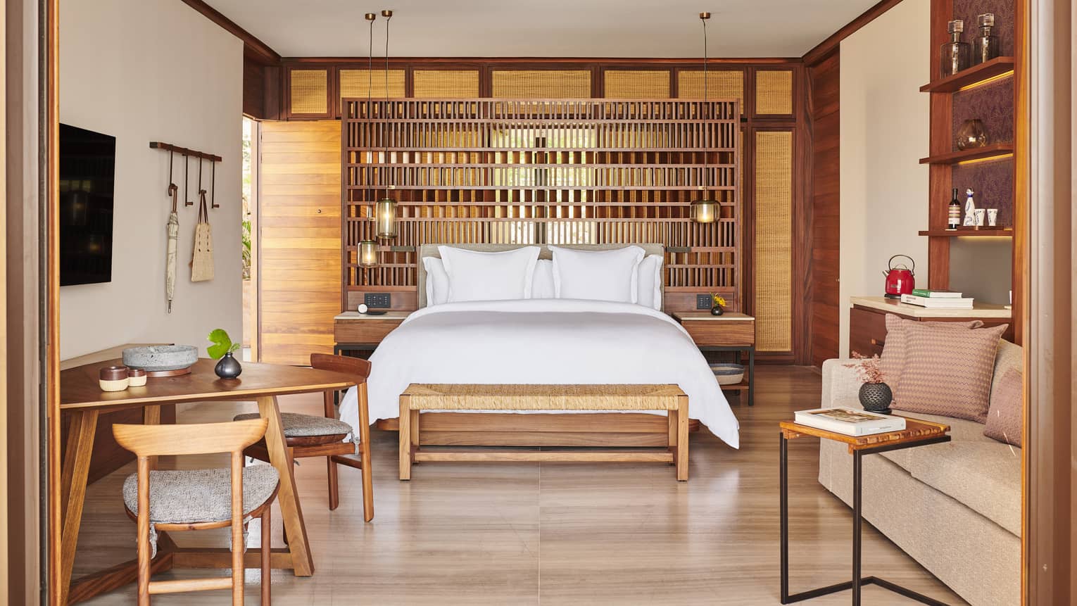 The interior of a beachfront room with a bed, shelves, small tables, chairs and sofa.