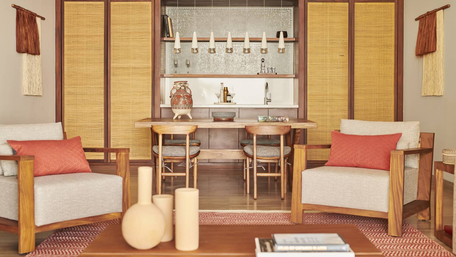 An interior of a suite with pink and warm colours, two chairs and a table with chairs.