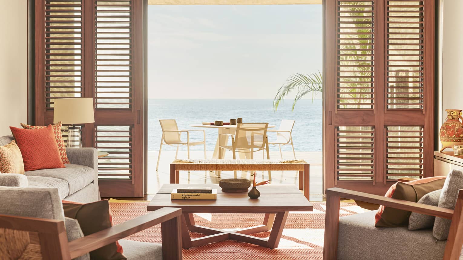 A room interior with an open door looking out at a small table with the ocean in the distance.