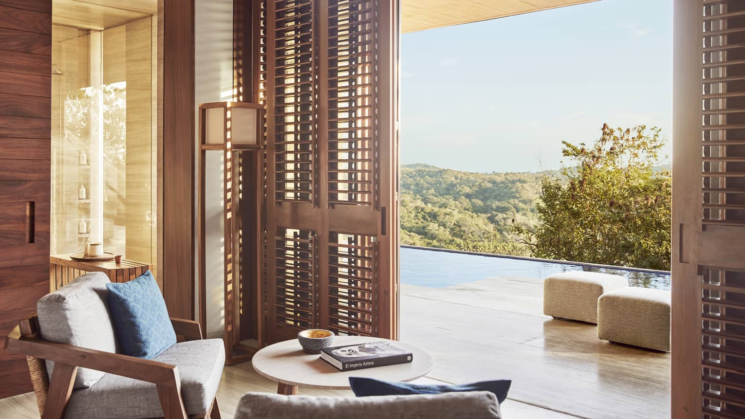 Sitting area of a resort suite, opening to a private terrace with infinity pool