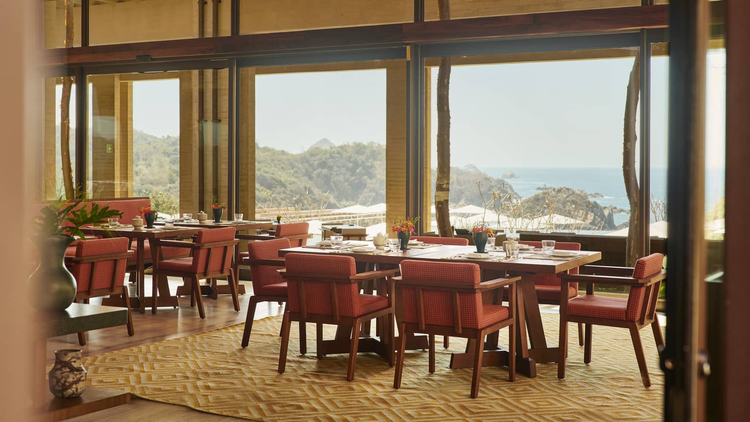 A restaurant with warm coloured chairs and large windows.