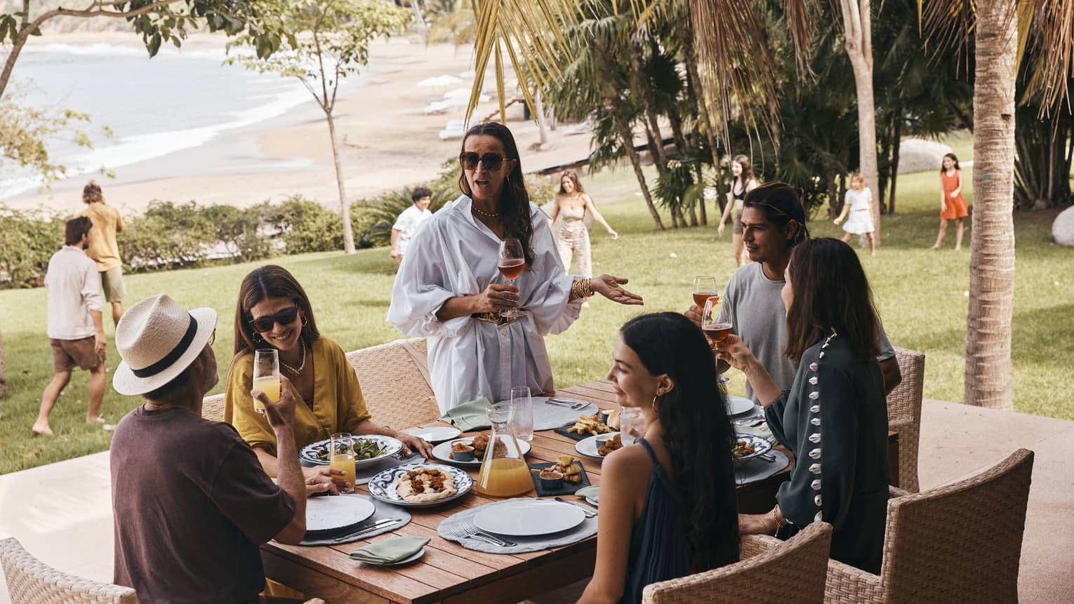 Friends and family enjoying a meal and kids playing in the background