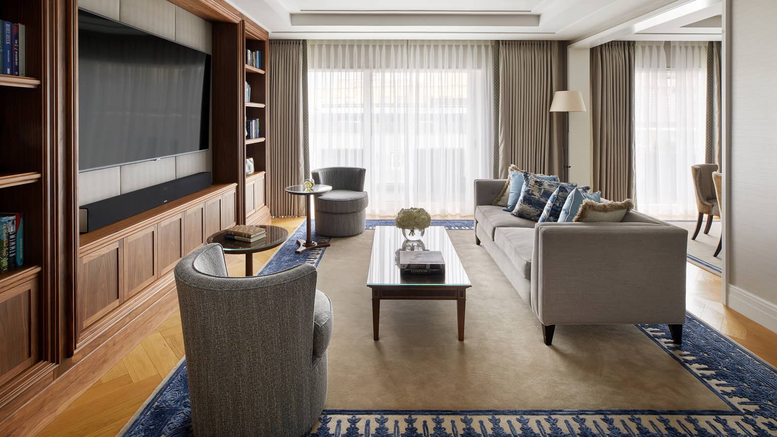 A living room area with a sofa, two chairs, a coffee table, two small side tables and large window.