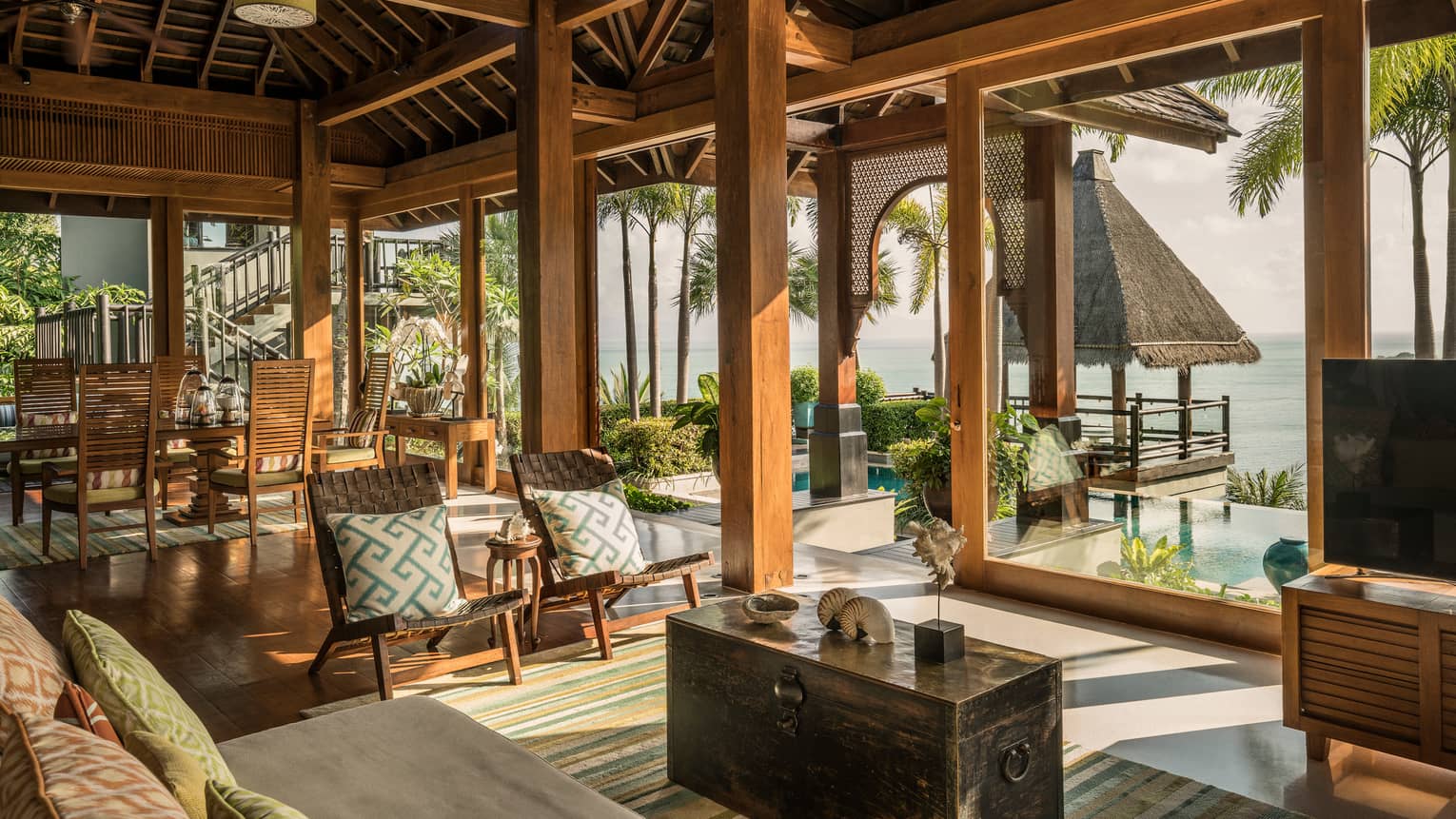 Bright, open air living and dining room, seats under rustic wood beam ceilings
