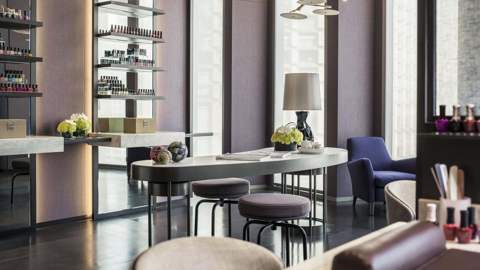 Serene nail bar with white table, blue chair, lamp, nail polishes in background