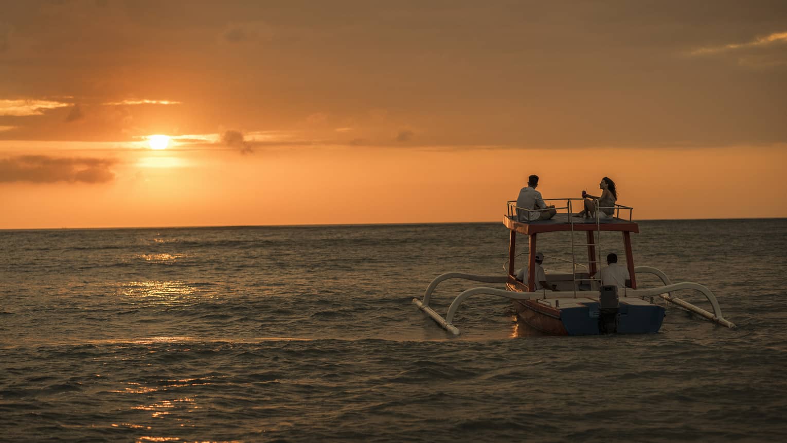 Sunset cruise boat on water under orange sky