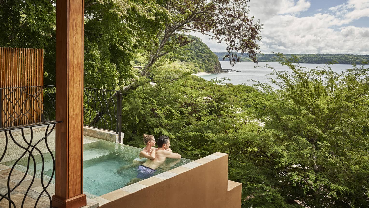 Couple in private plunge pool looking out to trees and ocean