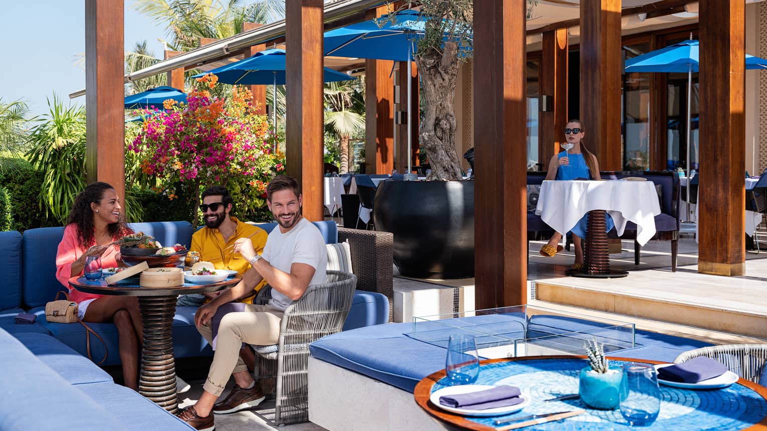 A group of people sit at an outdoor cafe eating a meal.