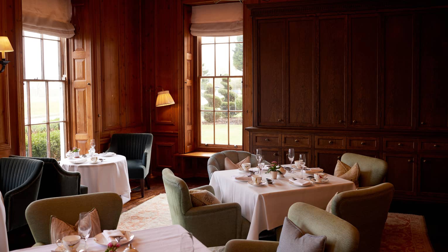 Cosy lounge with wood-panelled walls, small tables and chairs and dim lighting
