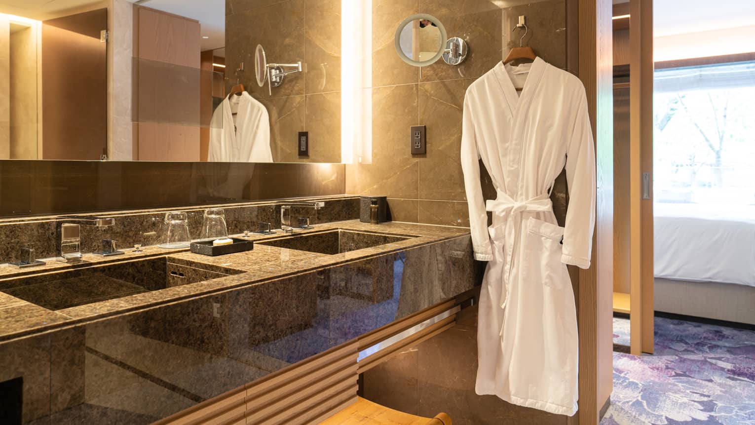 Luxury bathroom with a double-sink vanity, large mirror and a plush white robe hanging beside the counter