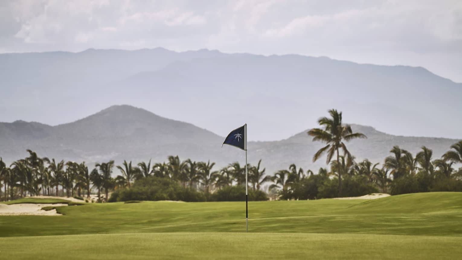 A putting green with a view of tropical trees and mountains behind