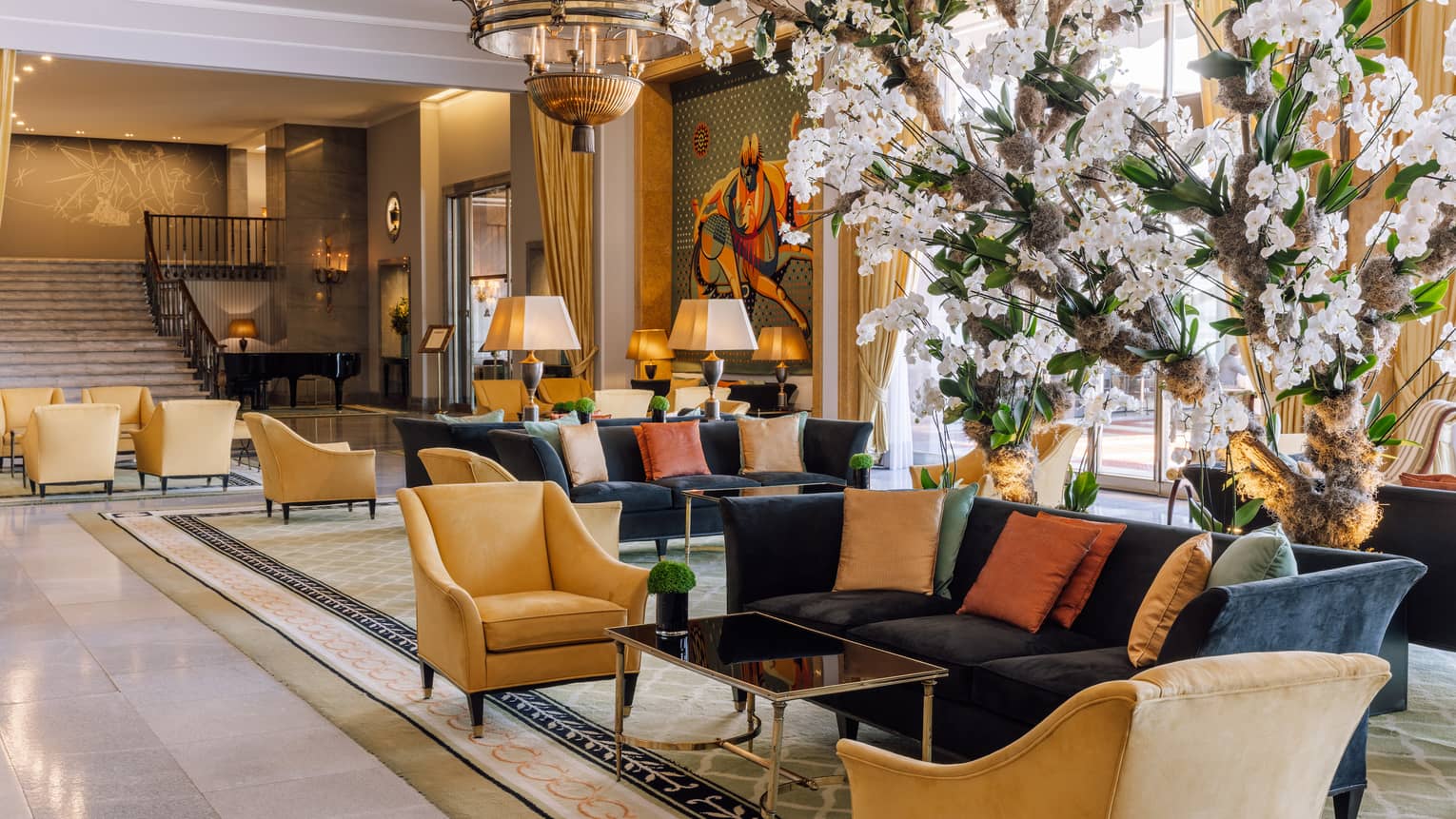 A lobby area with sofas, chairs and white flowers.