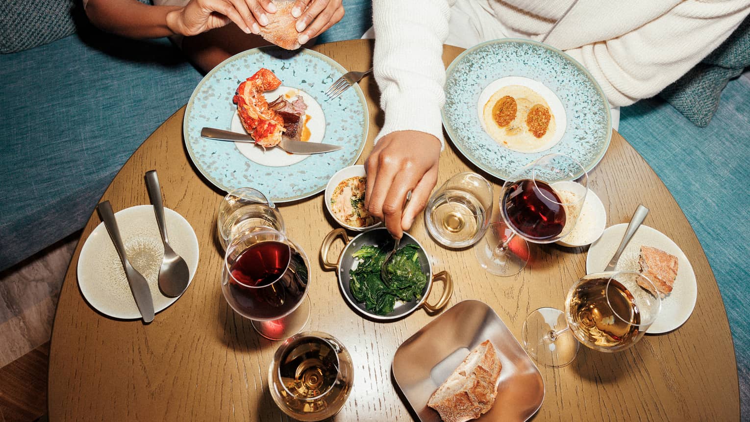 Two people sitting at a table with various food and drinks.