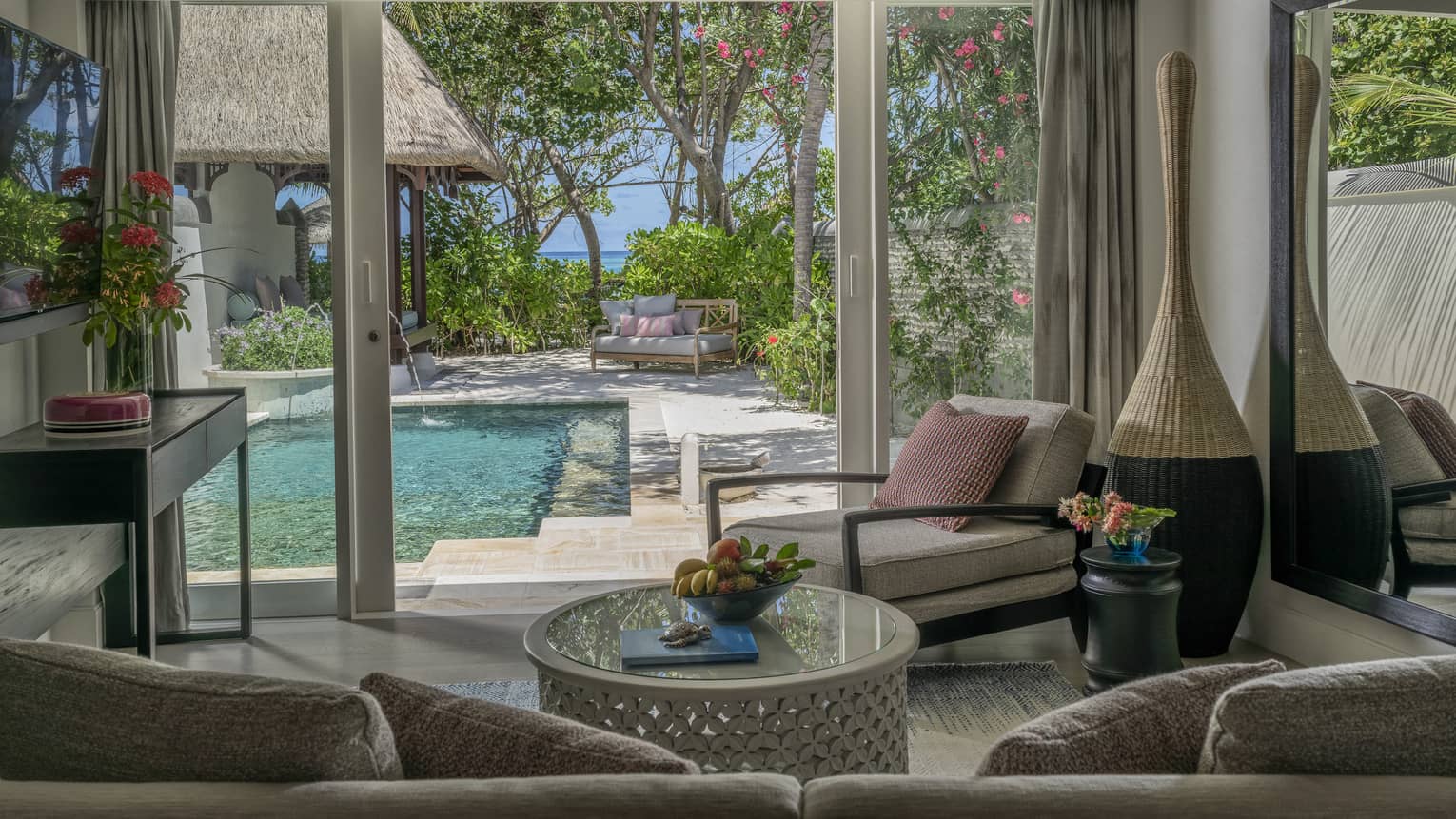 Living room opening to pool deck, with beach in the distance