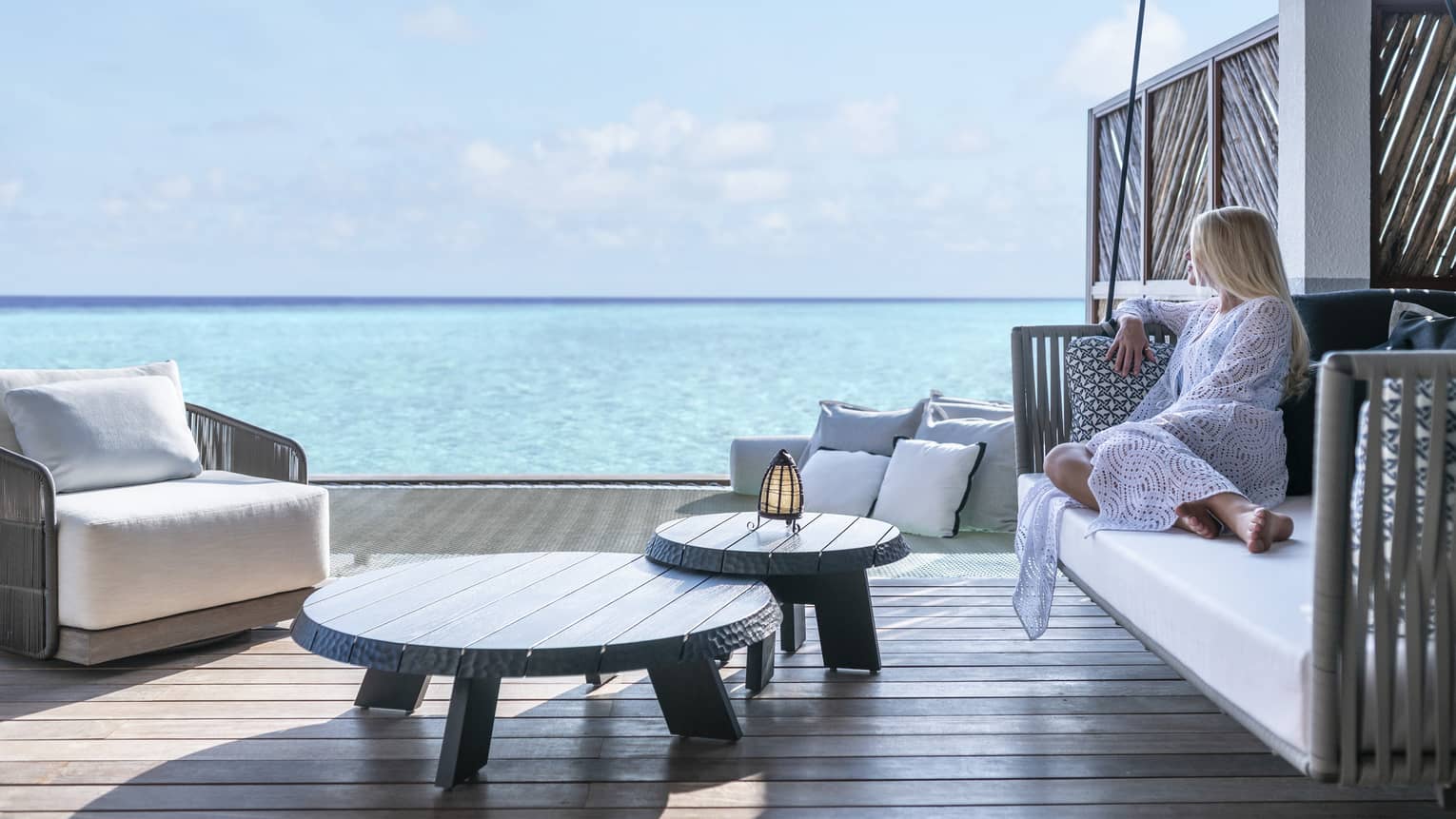 A guest relaxes on a swinging bench on a patio overlooking the ocean