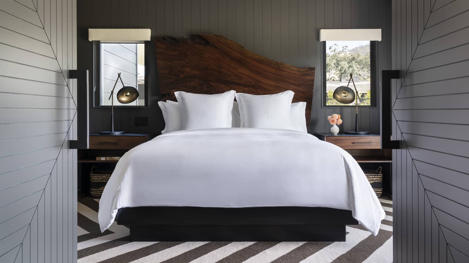 Stylish bedroom with black and white striped floor, wooden headboard