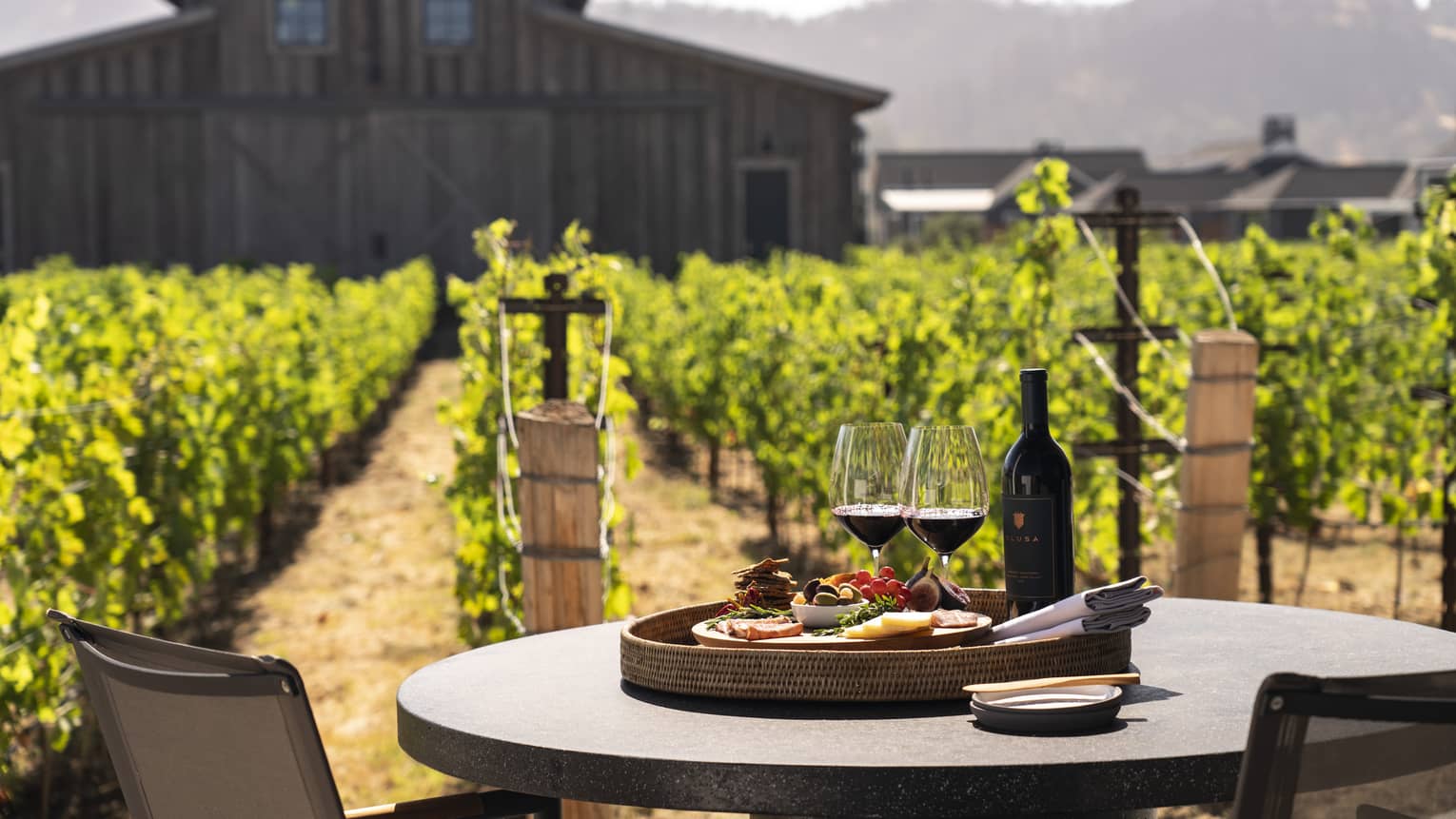 Two wine glasses with a plate of snacks on an outdoor dining table.