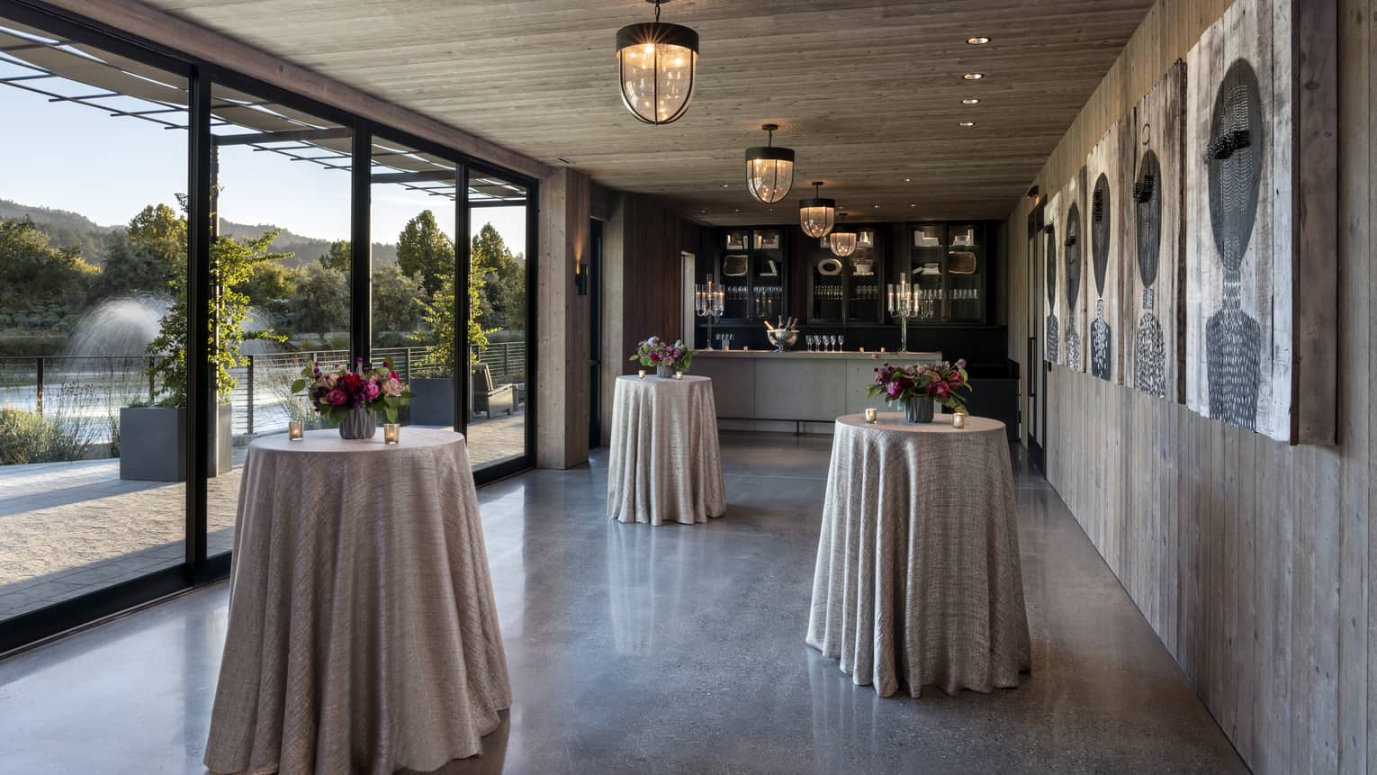 A small room with small round tables, counters and large windows.