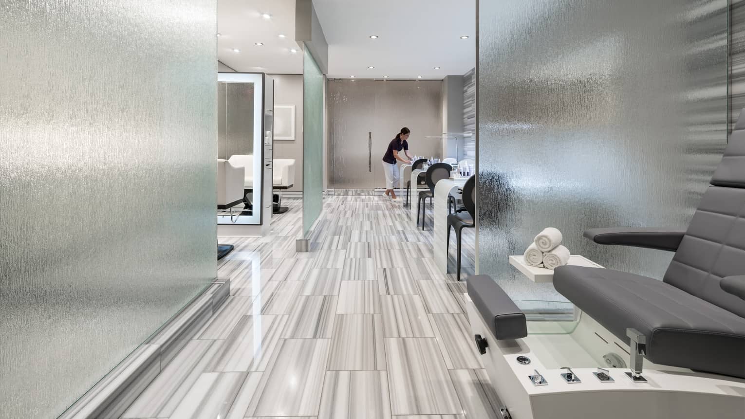 Spa staff sets up table in modern salon with frosted glass panels