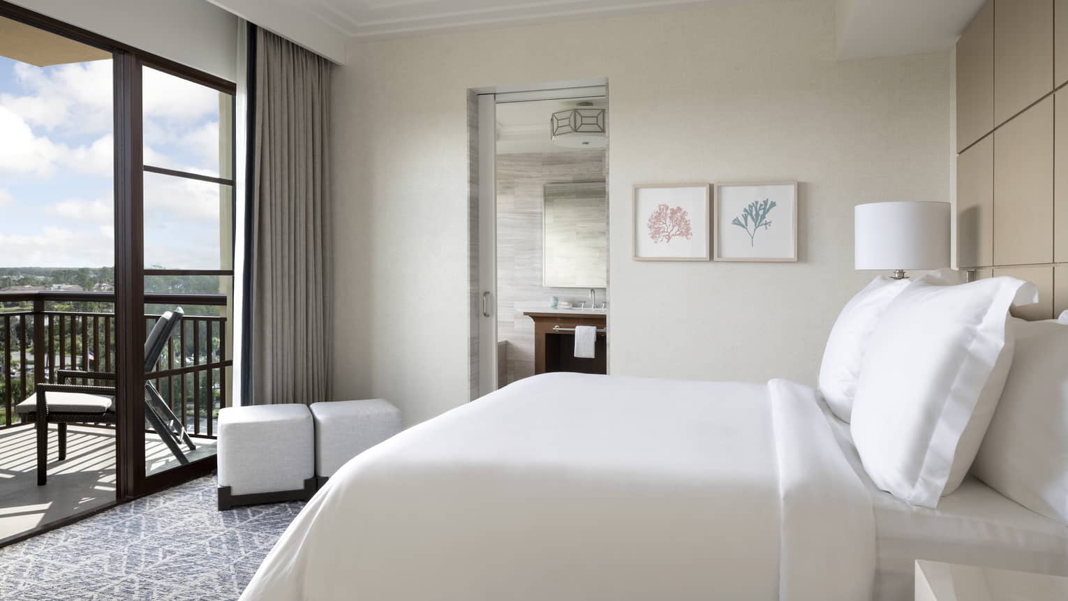 Hotel room with white king bed, wooden head board, walk-out balcony