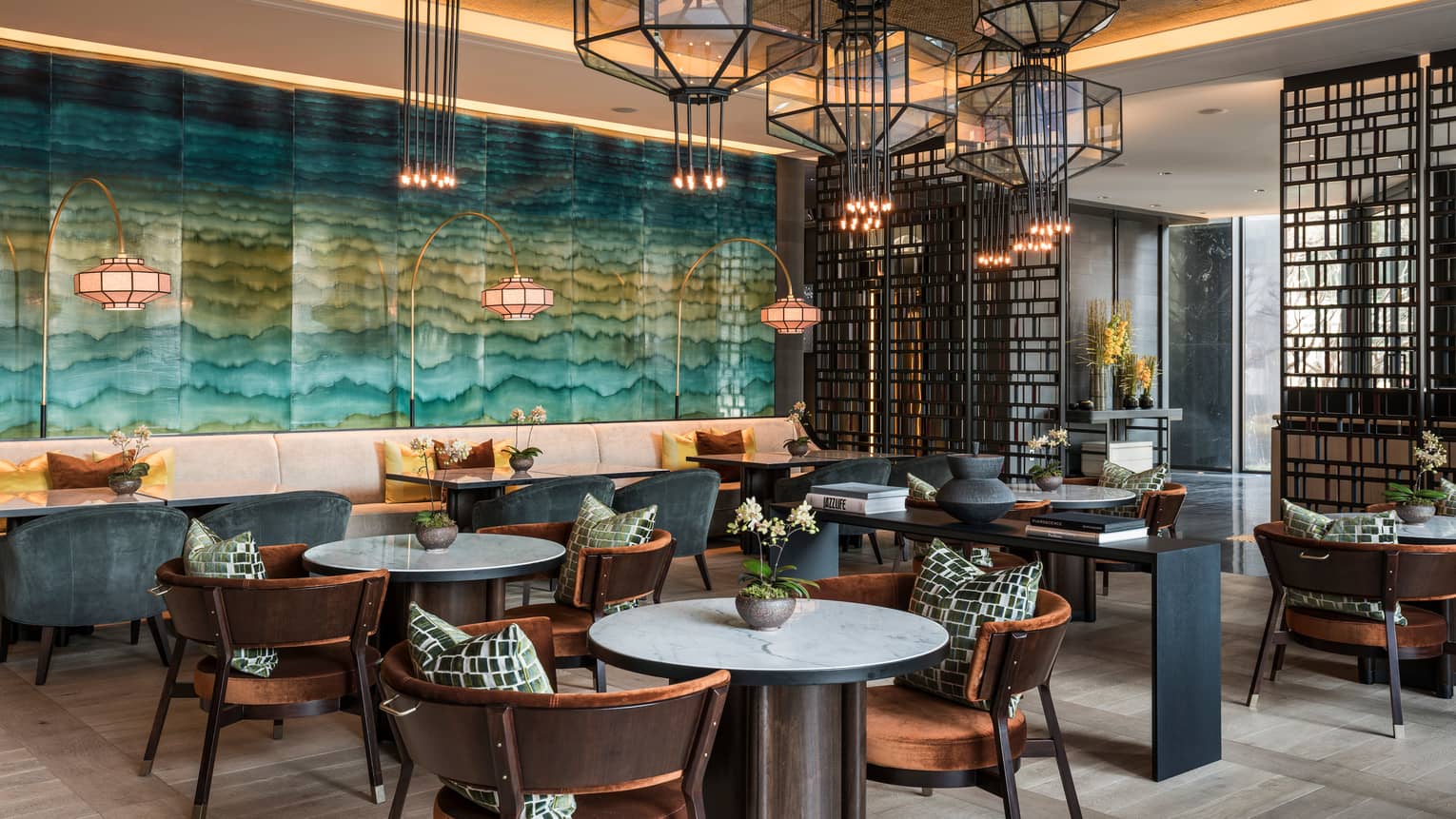 Maru dining tables, chairs by glass accent wall with teal wave design