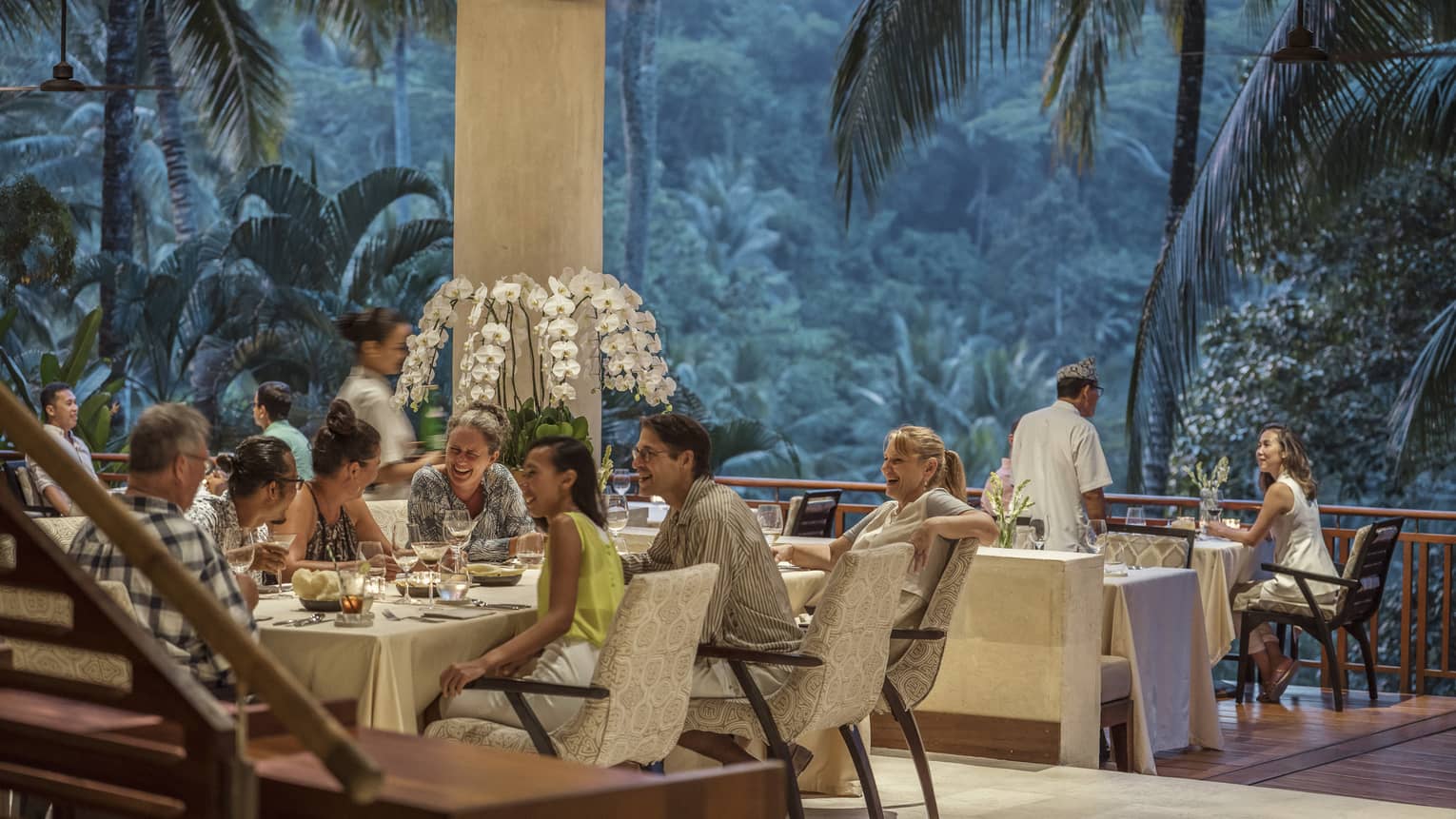 Groups of smiling friends dine in open-air Ayung Terrace restaurant