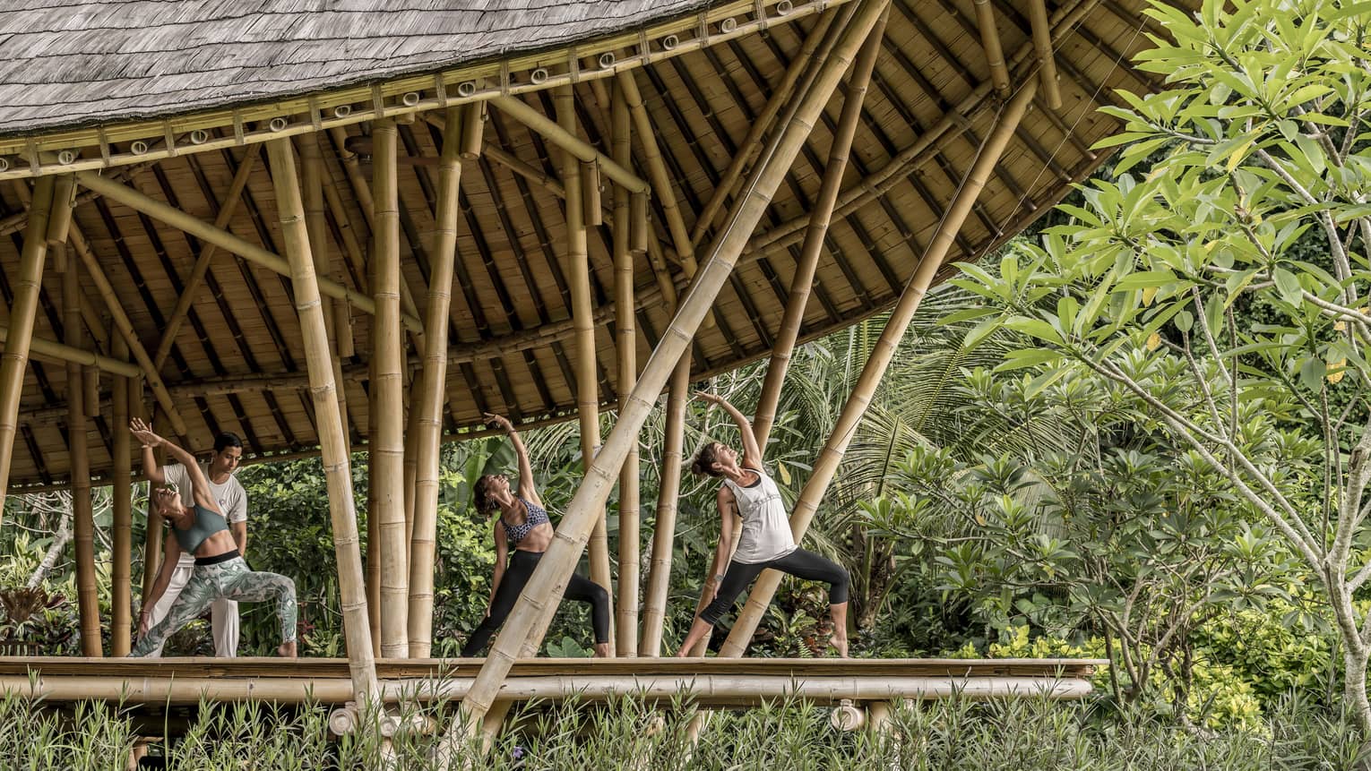 Guests reaching towards the sky while participating in an outdoor yoga class in Bali