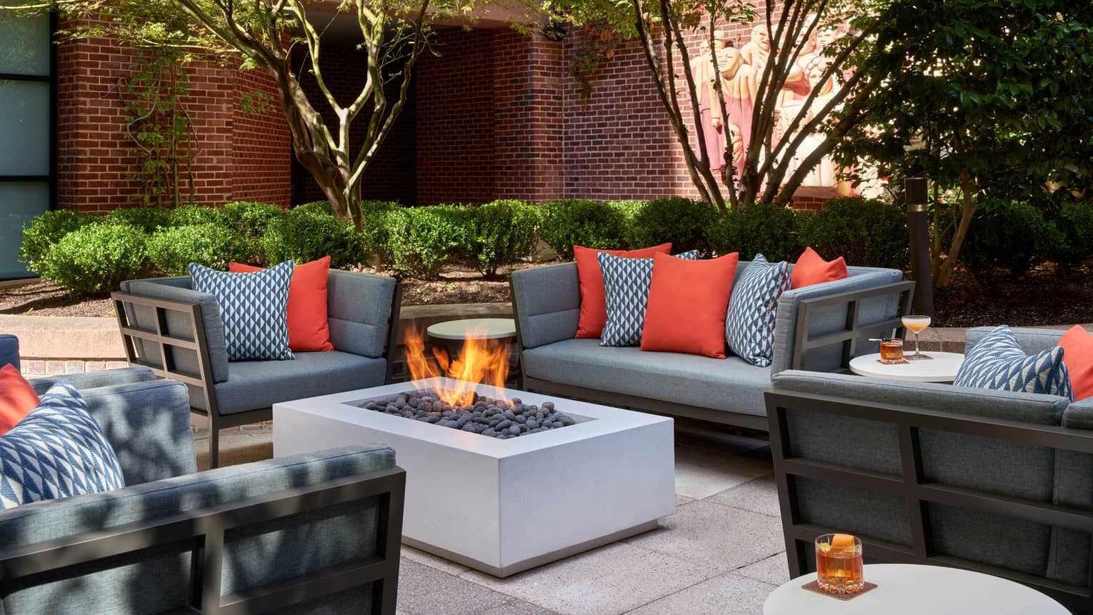 A fire pit outside surrounded by sofa and chairs.