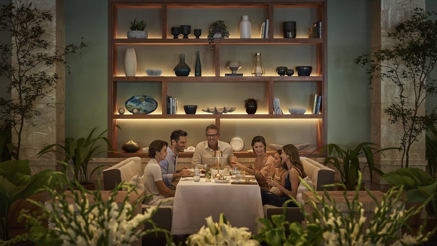 A group of people sat at a dining table, eating dinner together.