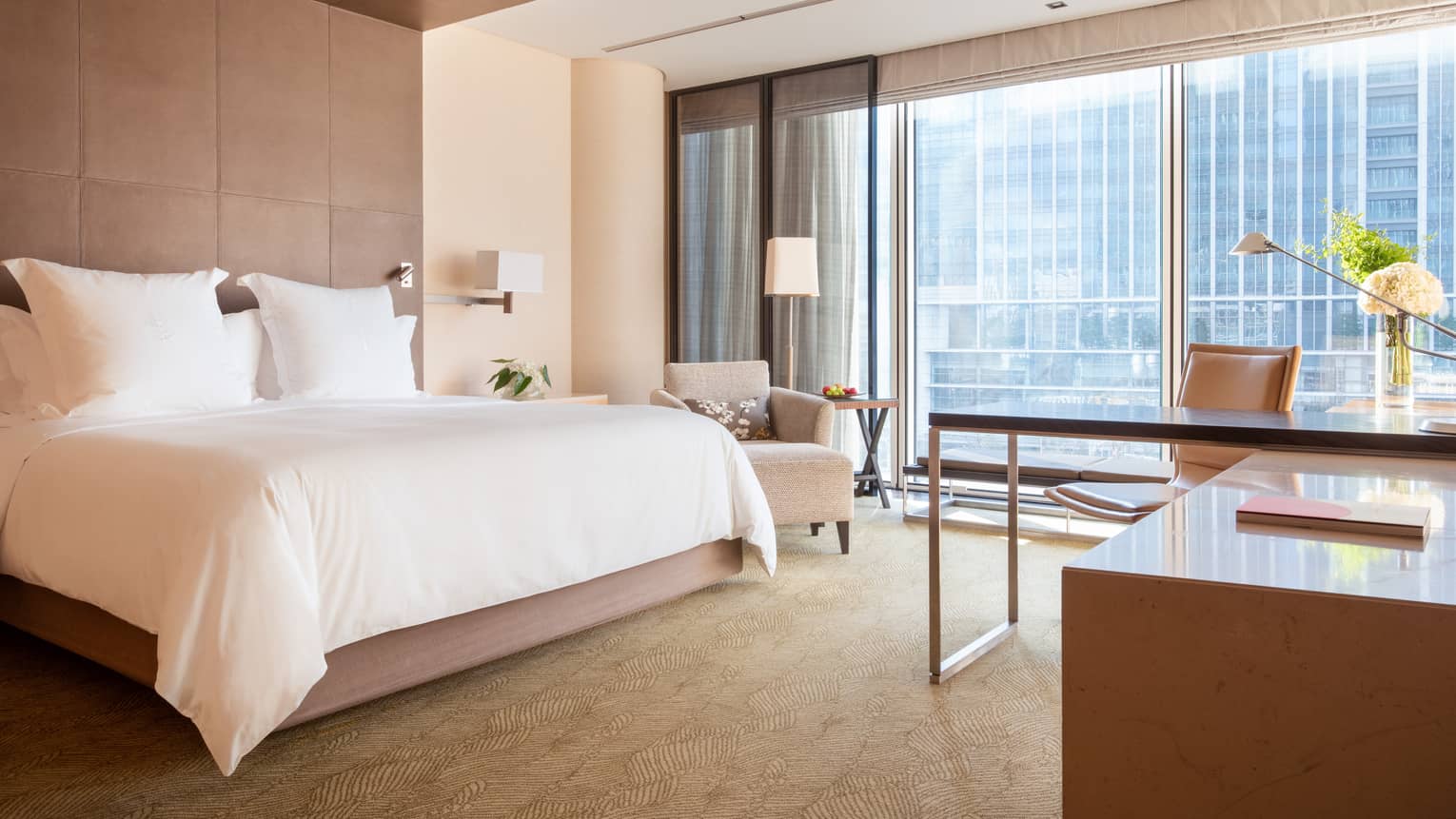 Deluxe City View Room with floor-to-ceiling windows looking out onto the skyline and a desk area