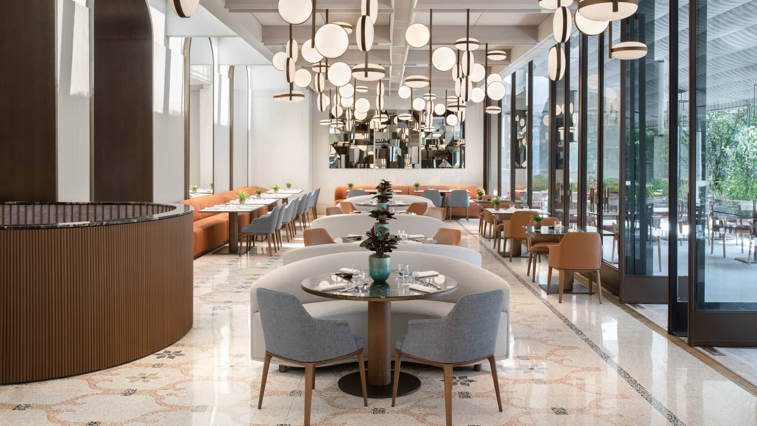 A cleanly decorated dining room with an array of unique lighting fixtures above