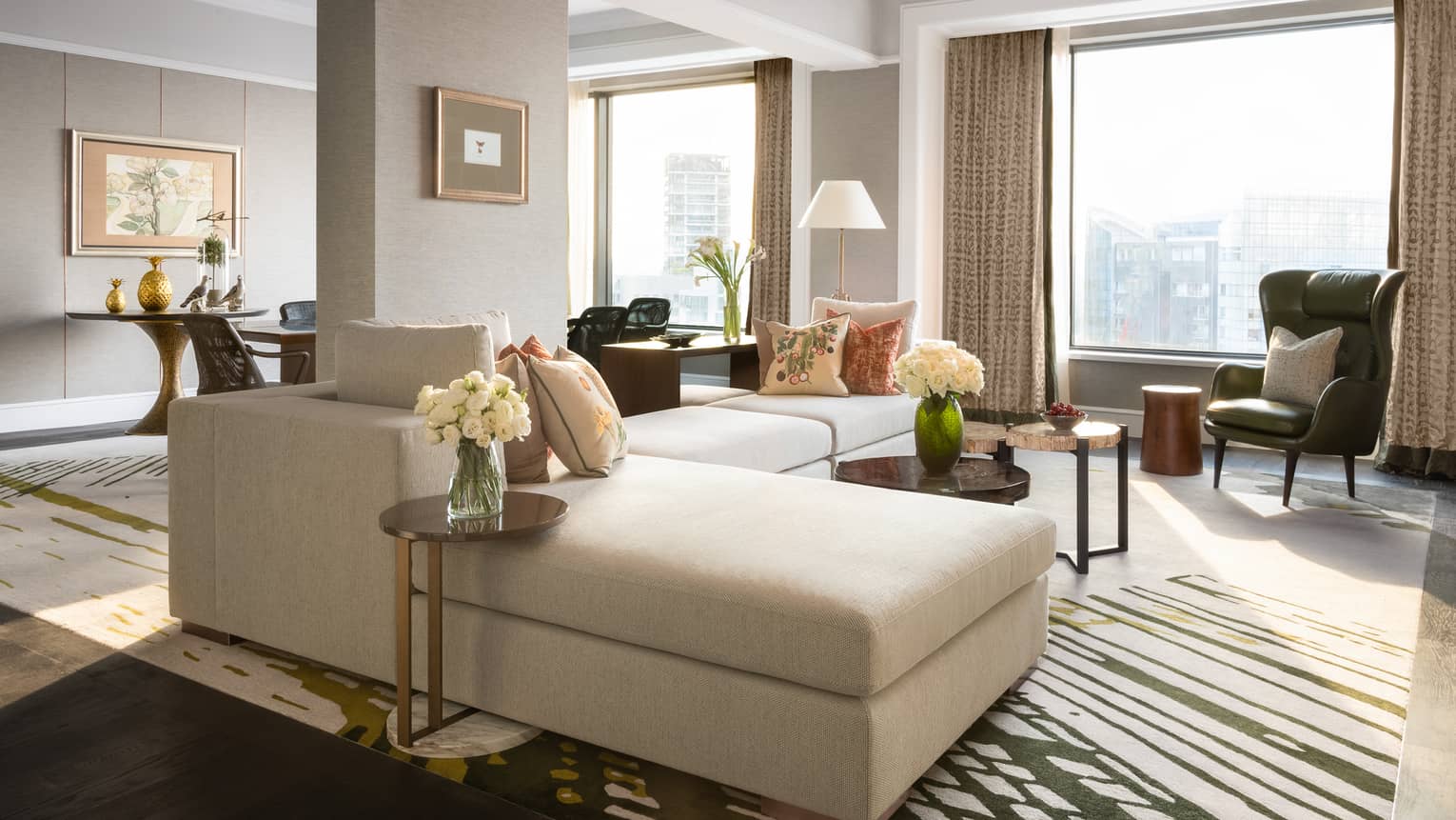 Living area of Royal Suite with cream couch, pillows, white flowers, decor 