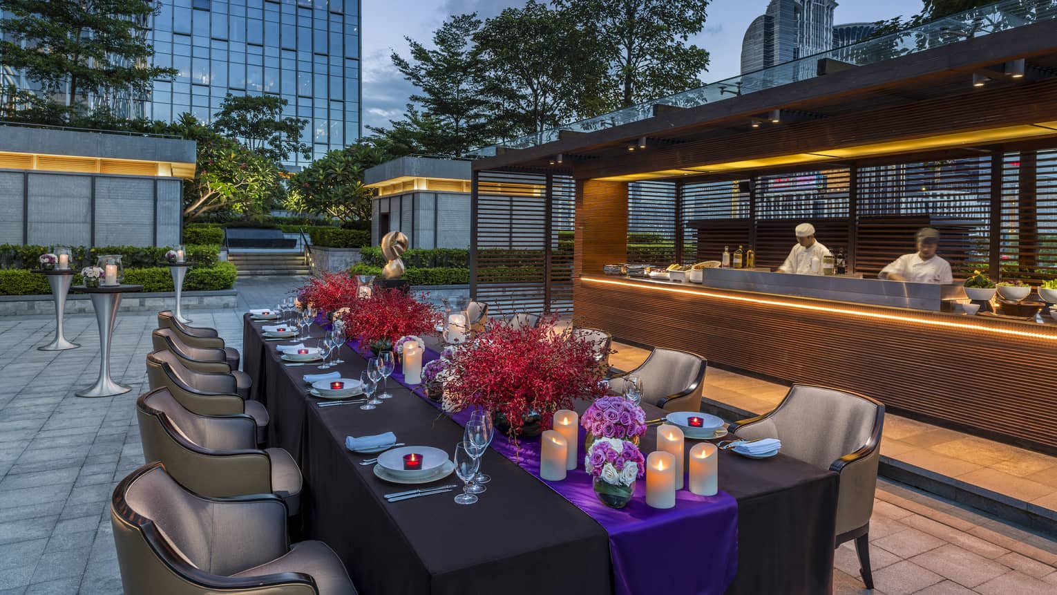 Terrace BBQ private dining table with candles, flowers on patio by bar with chefs