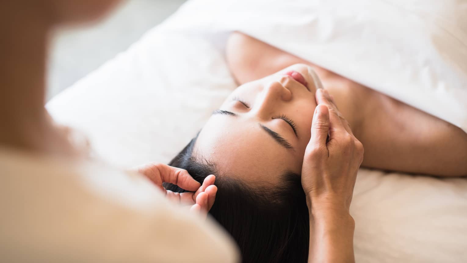 A guest receiving a soothing facial at a spa, lying on a massage table, surrounded by calming décor and soft lighting.