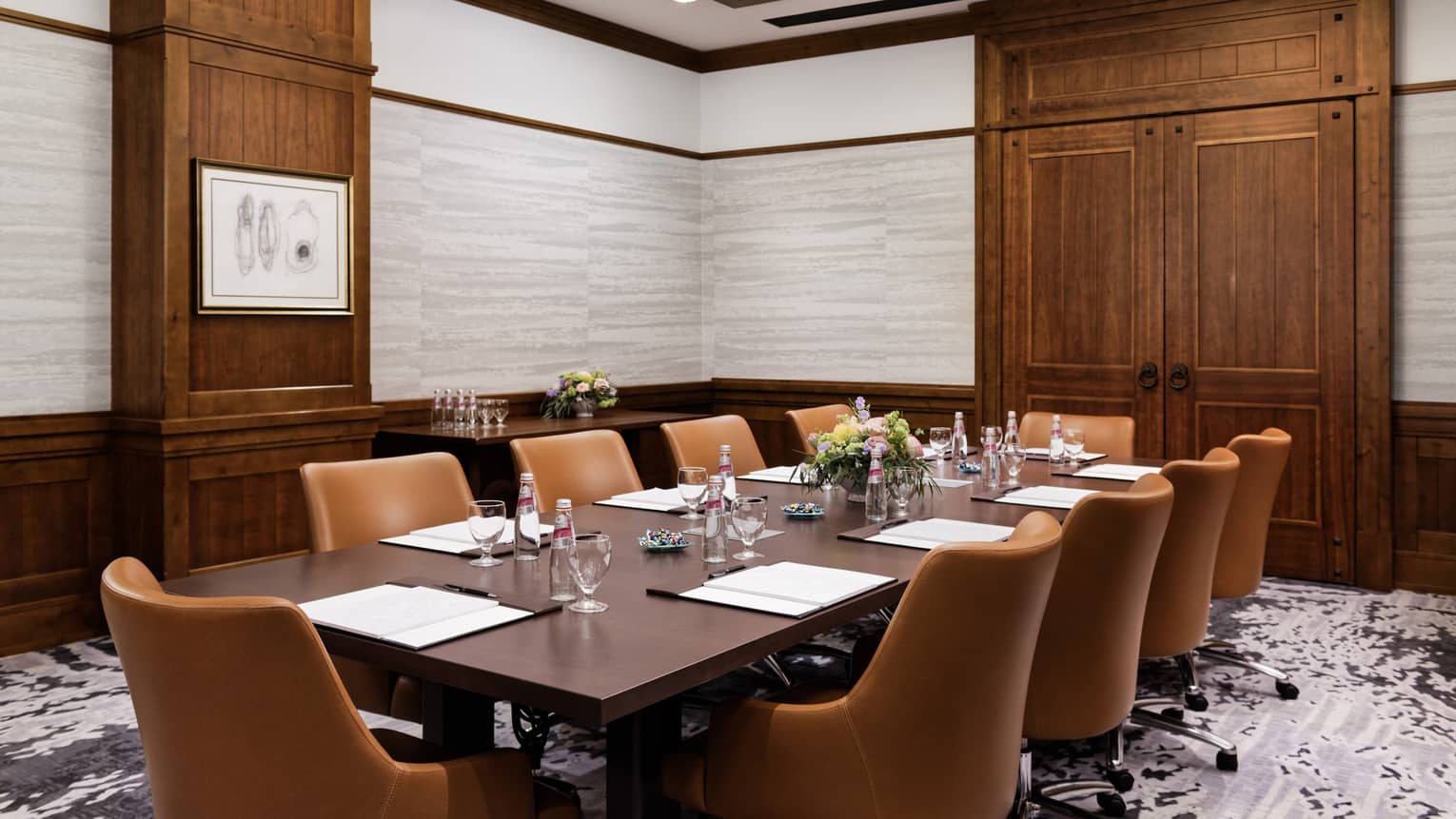 A meeting room with a large table, brown chairs and wooden door.