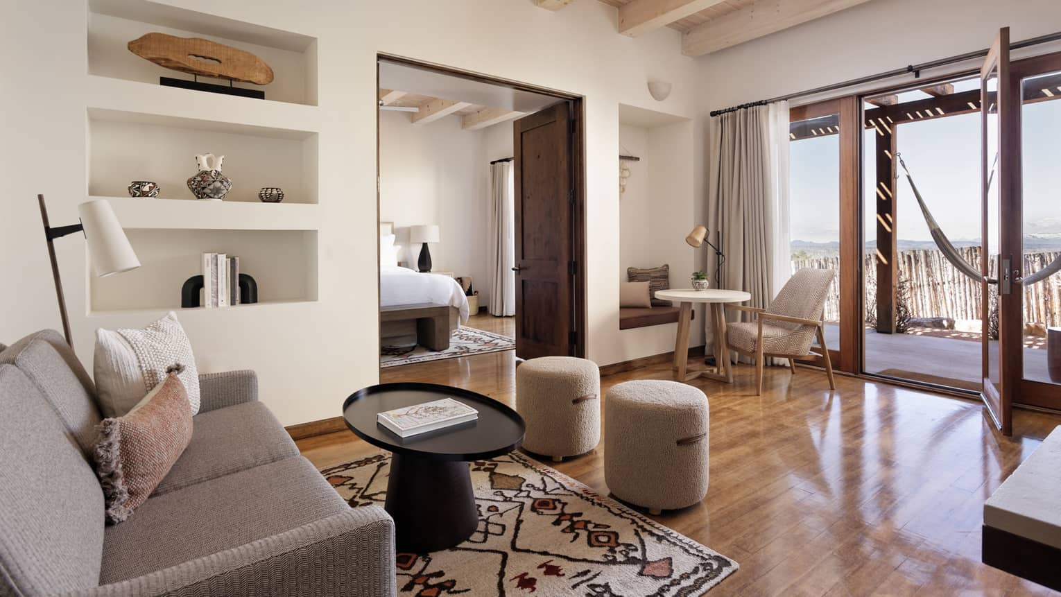 A living room in a suite with a couch and coffee table, and hammock on the patio