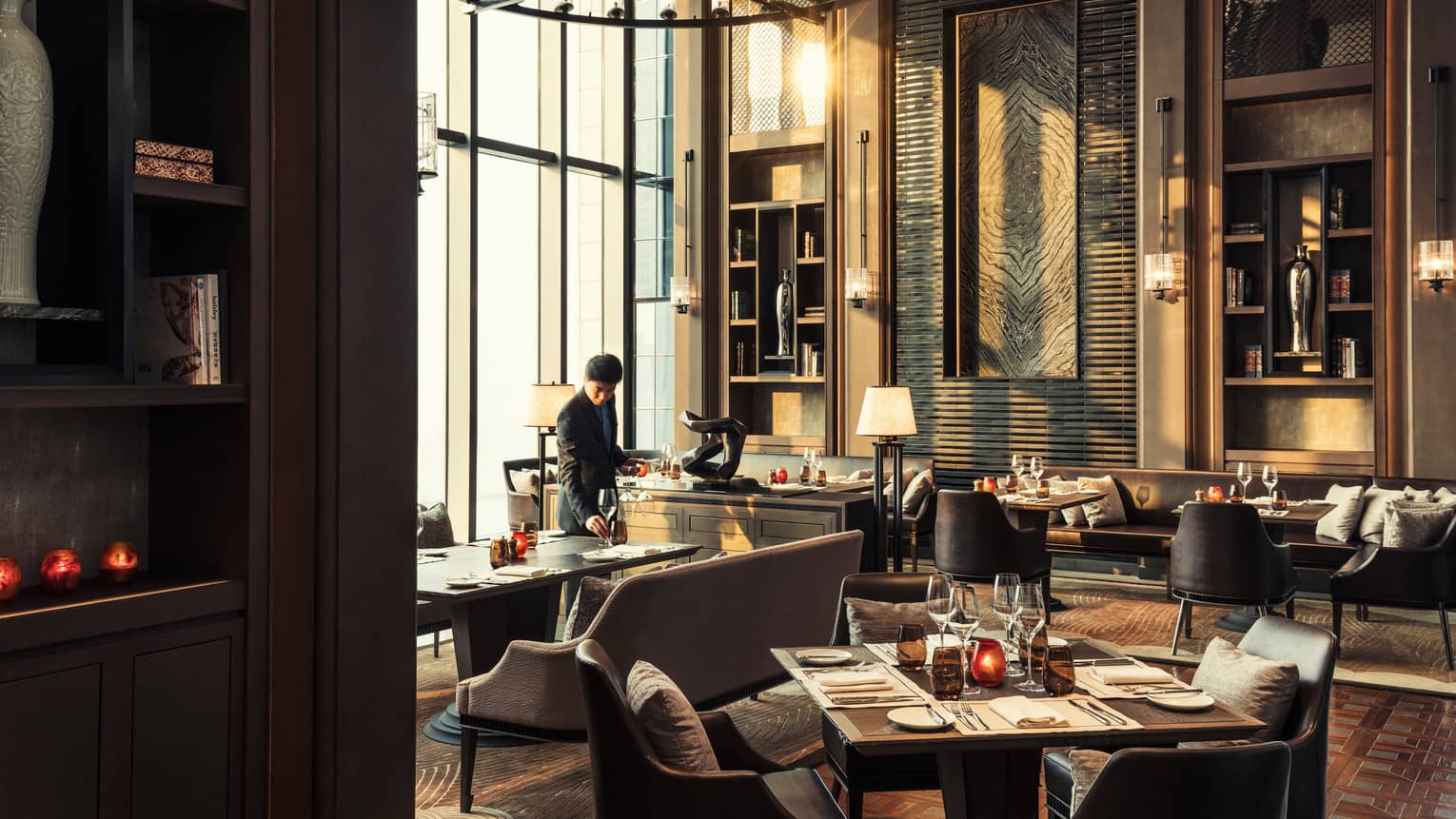 Server sets wine glass on table in formal Cielo dining room with tall windows, ceilings