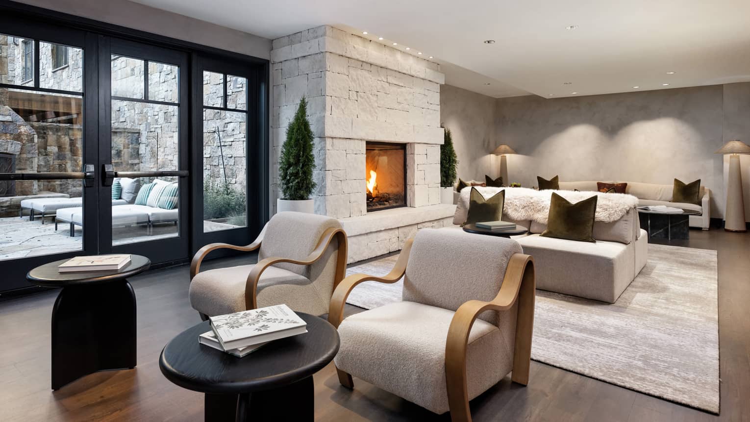 Spa relaxation area with cream sofas and armchairs, in-wall fireplace, glass doors leading to terrace with lounge chairs
