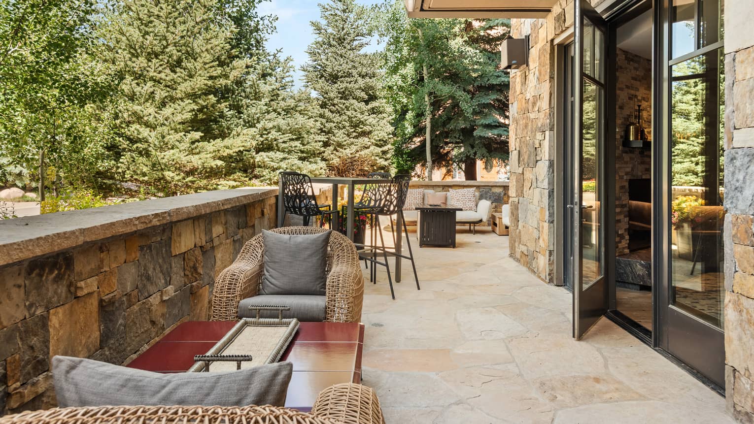 A patio with chairs and tables and a door leading inside.